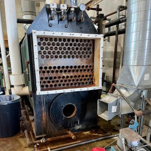 Boiler unit with visible tubes and gauges in a brewery setting, illustrating Kelly Boiler's repair and servicing work.